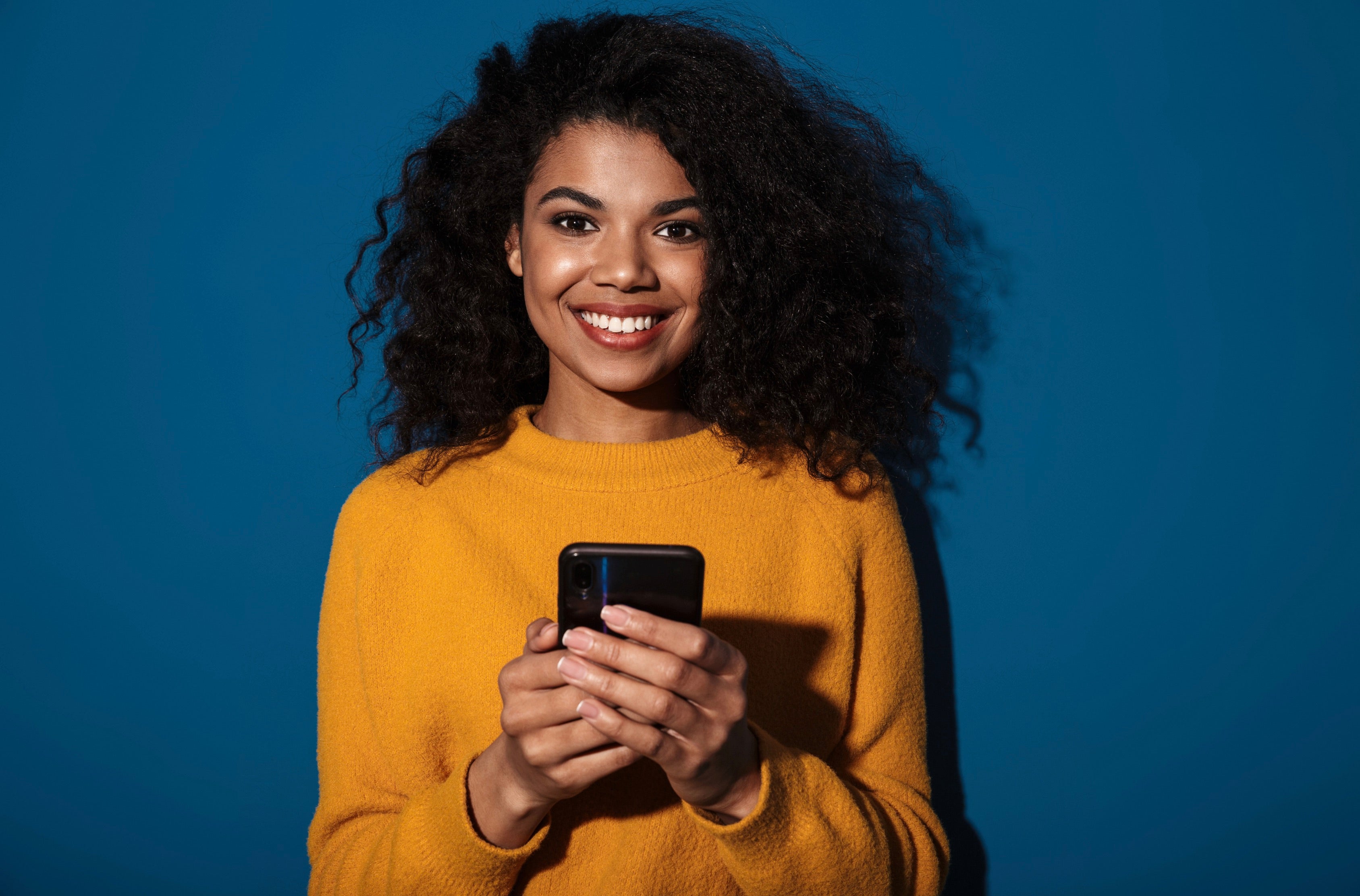 A woman is smiling with phone in hand